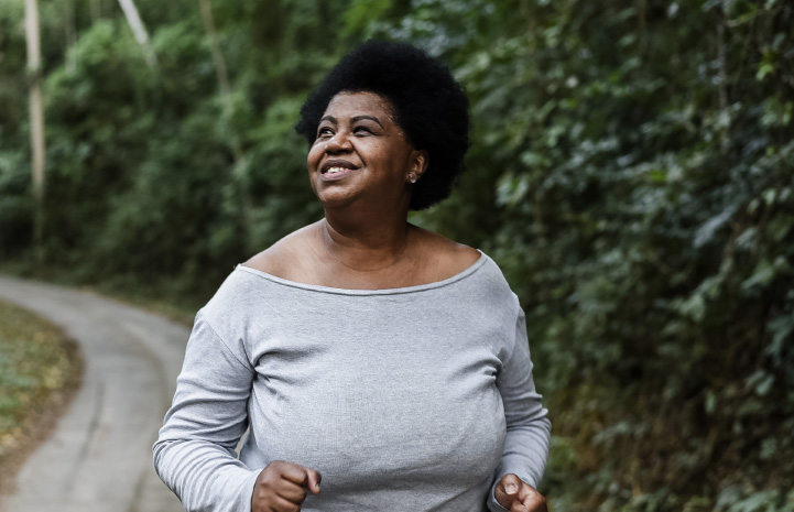 Woman running on a small path next to a dense jungle.