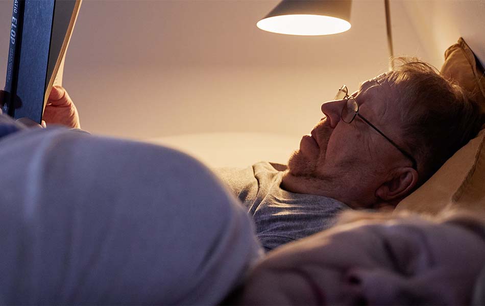 Old man lying on the bed and reading book