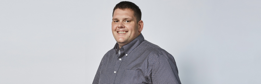 Man wearing a grey shirt smiling.