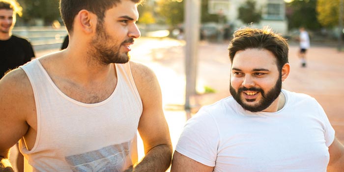 Two men in casual attire engaged in a conversation, representing the societal expectations of masculinity and self-reliance.