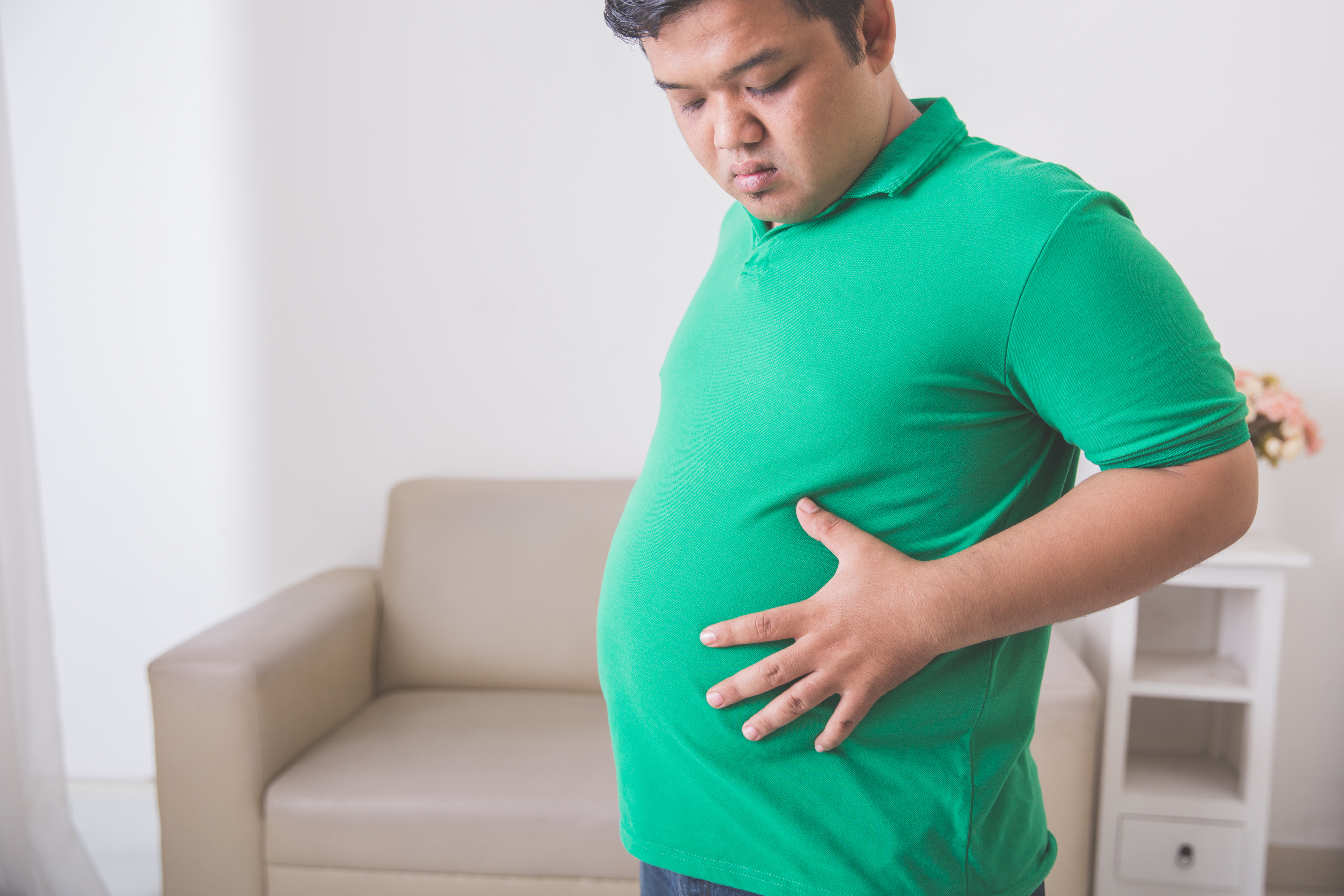 Portrait of overweight obese man holding his big belly
