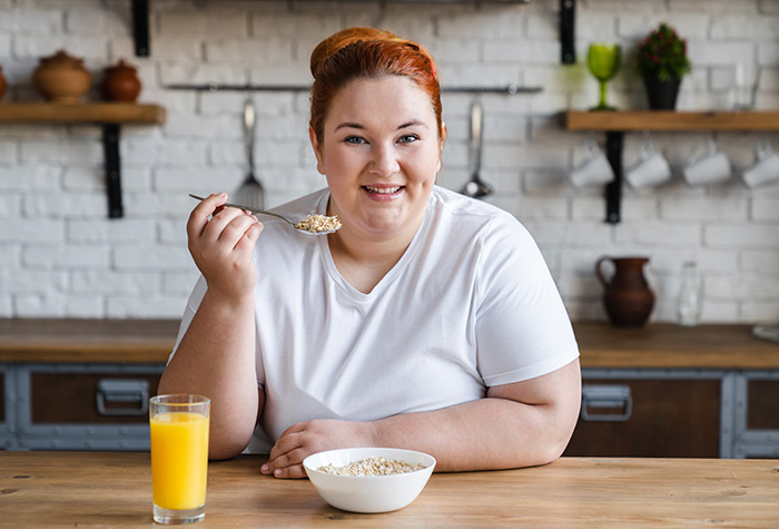Smilende kvinne spiser frokost Smilende kvinne spiser frokost