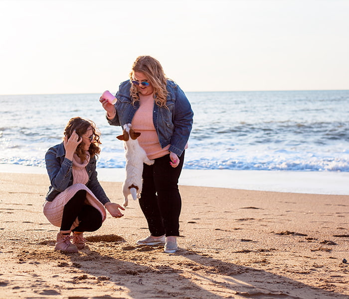 Overvektig kvinne leker med hund på stranda