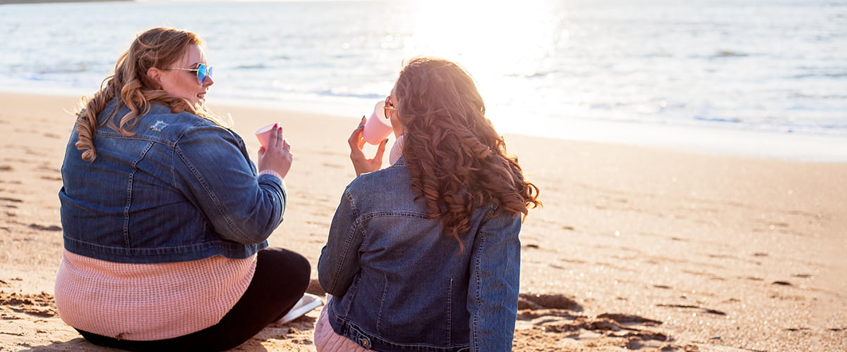 Overvektig kvinne i samtale med venn på stranda