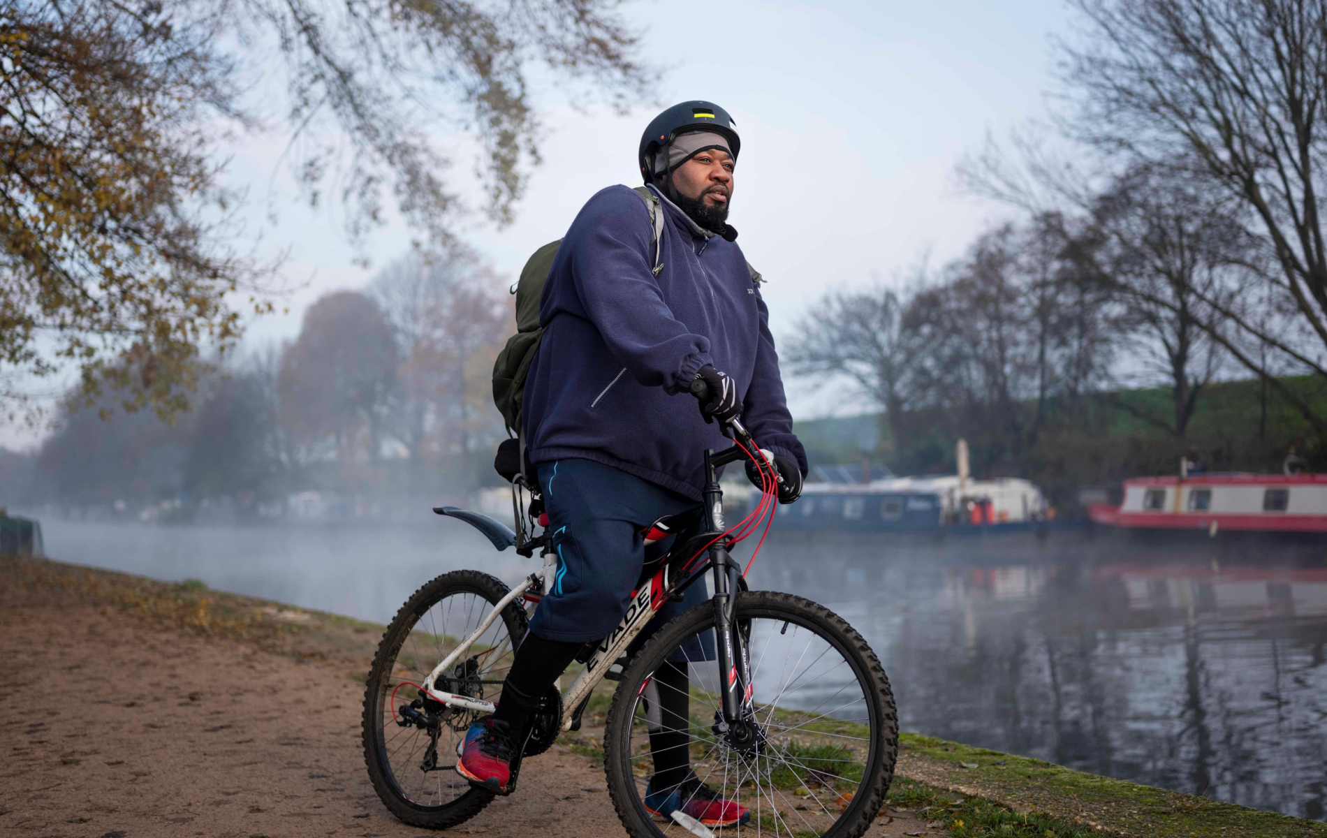 Pessoa com obesidade a andar de bicicleta num parque.