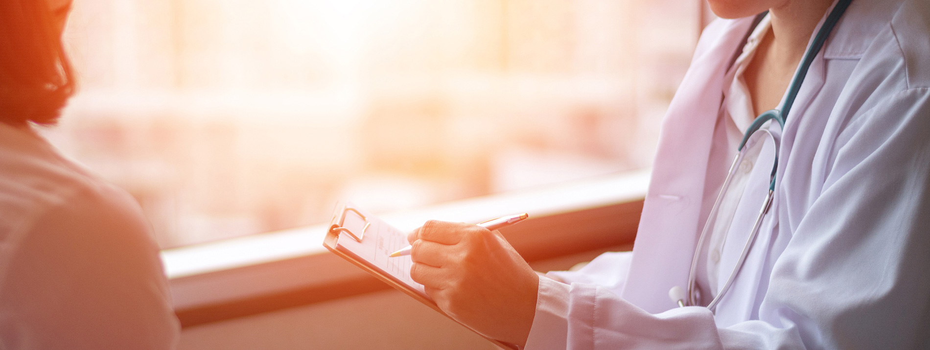 A female health care professional showing something on a notepad to a woman.