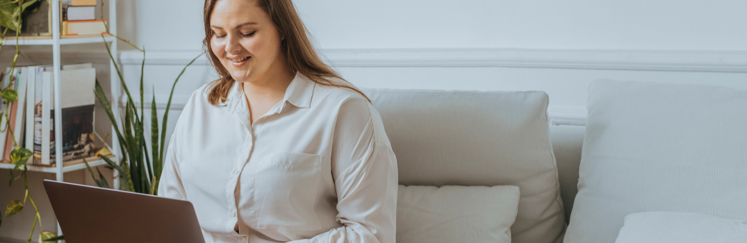 Woman sitting in a couch with a laptop.