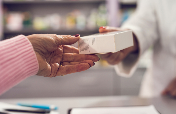 Medicine being handed from a healthcare professional to a recipient.