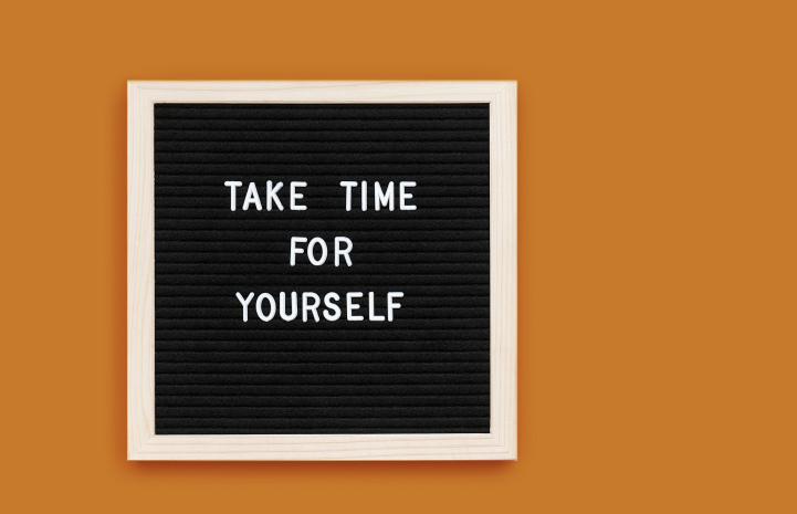 Take time for yourself written on a black framed background put on an orange wall.